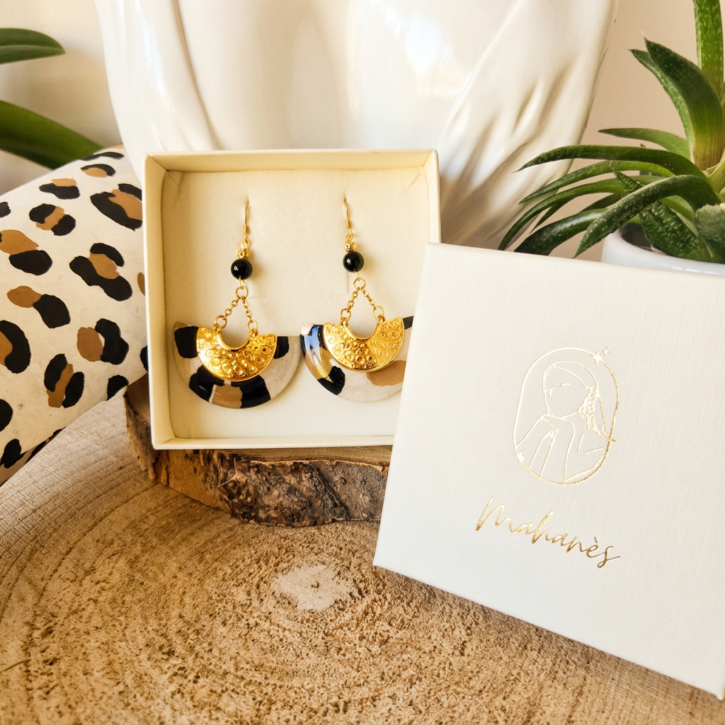 Boucles d'oreilles Ādhā Gōla présentées dans leur écrin, création artisanale en papier lokta motif léopard, finition résine haute brillance.