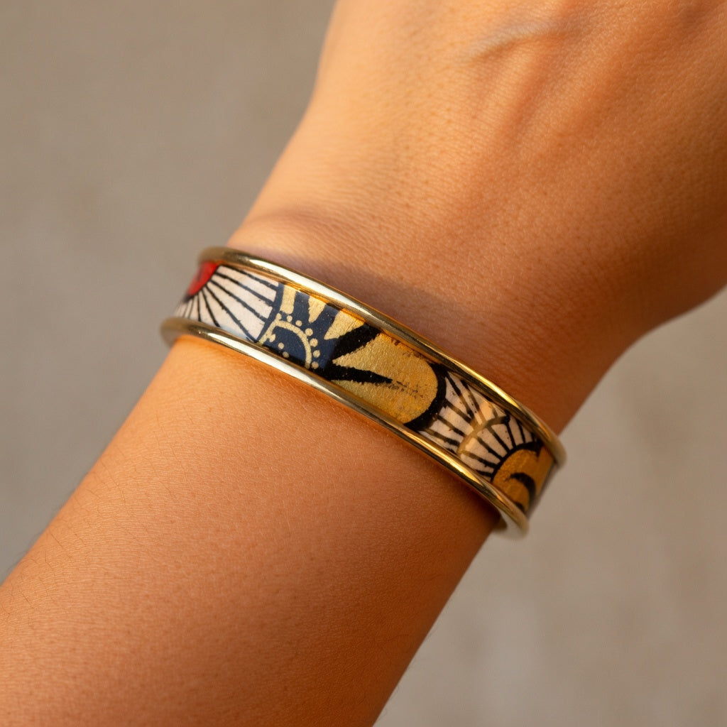Manchette dorée portée au poignet sur une tenue sobre, bijou ethnique-chic jaune et or pour femme.