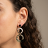 Boucles d'oreilles doubles cercles Nāca noir et doré spirales portées à l'oreille, bijou pendant fait main en France