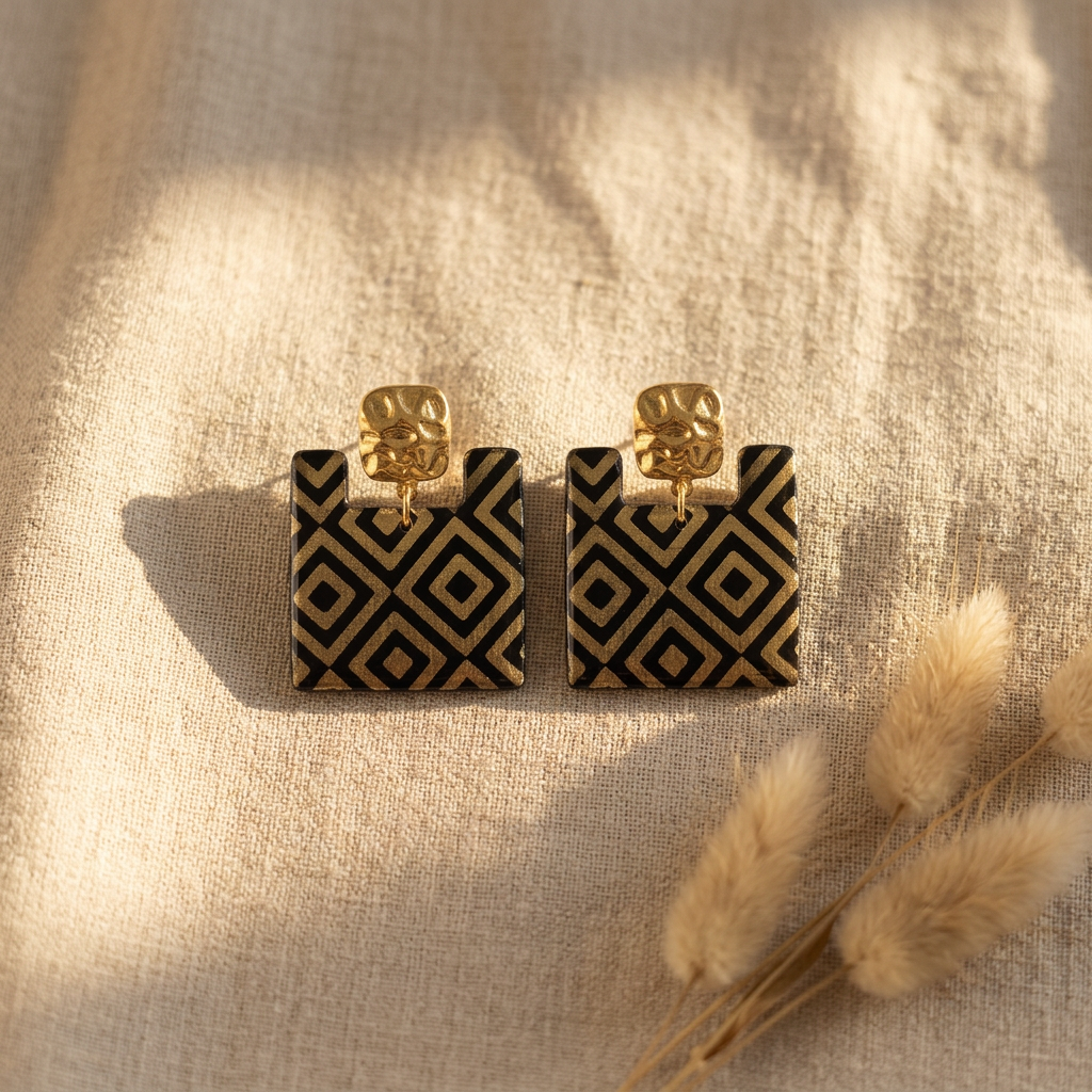 Boucles d'oreilles carrées fait main Ṭā'ila — papier indien losanges noir et or, clous carrés martelés dorés, 4cm